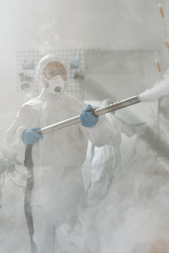 A person in full protective gear fumigating a room to ensure sterilization against viruses.